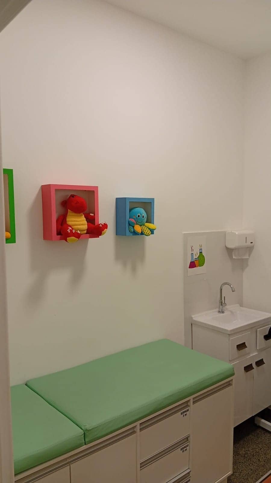 Sala infantil com maca, nichos coloridos e bichos de pelúcia.